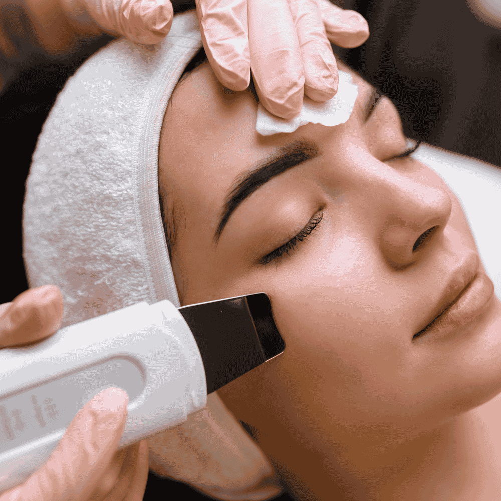 Tratamiento facial: Una mujer recibe una exfoliación facial en un spa con guantes.