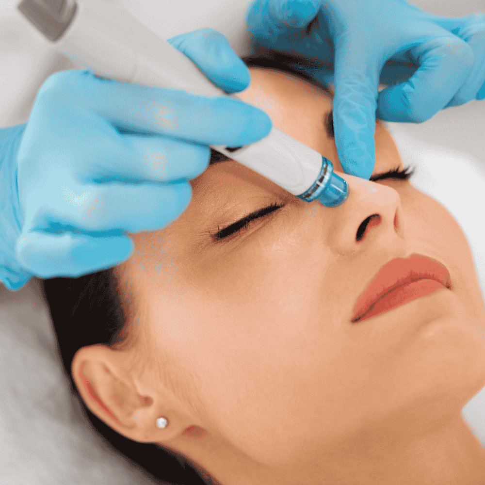 Tratamiento facial realizado en la cara de una persona con un dispositivo portátil y guantes azules.