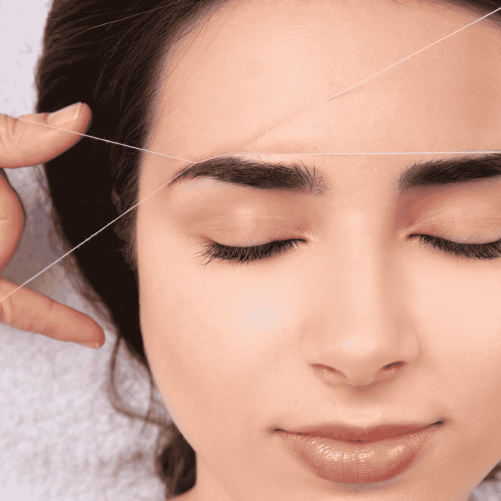 Depilación de cejas con hilo: Se utiliza hilo para dar forma a las cejas. Ojos cerrados, piel clara.
