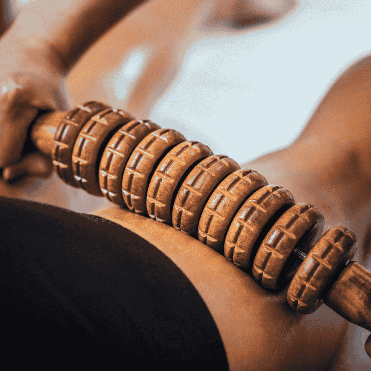 Rodillo de masaje de madera utilizado en la pierna de una persona.