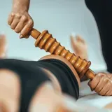 Rodillo de masaje de madera utilizado en la pierna de una persona.