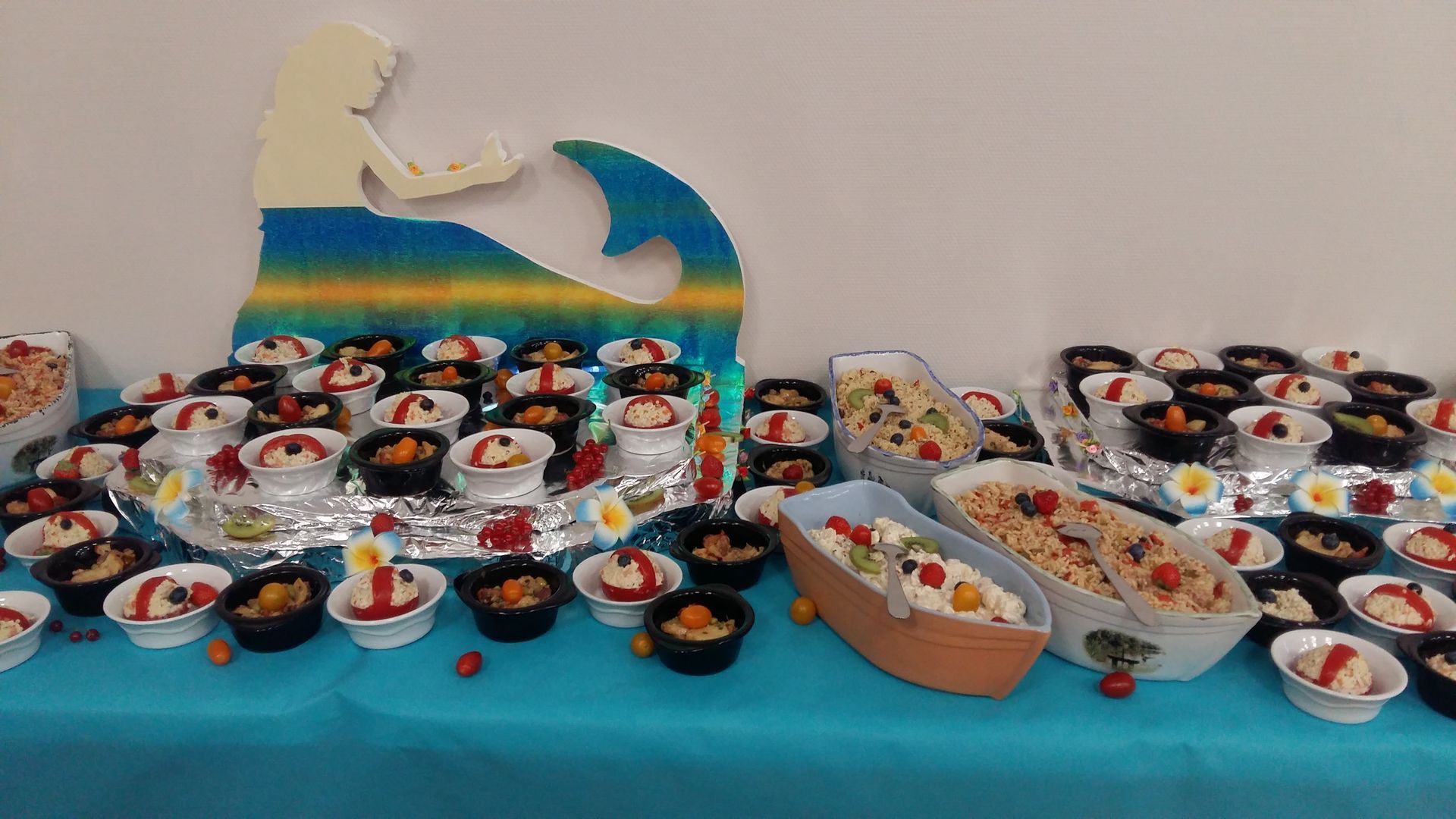 Table de desserts avec décor de sirène et plusieurs bols de glace avec garnitures de fruits.