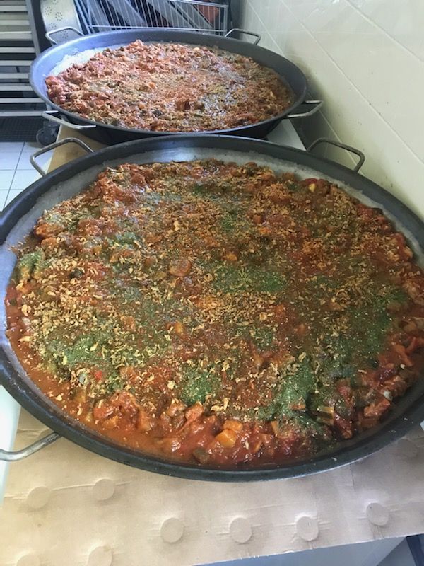 Deux grandes casseroles de nourriture cuite avec une garniture aux herbes vertes.