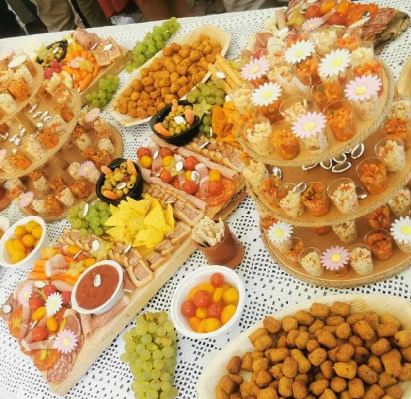 Une table dressée avec divers amuse-gueules, notamment des craquelins, des fruits et des trempettes, pour un rassemblement.