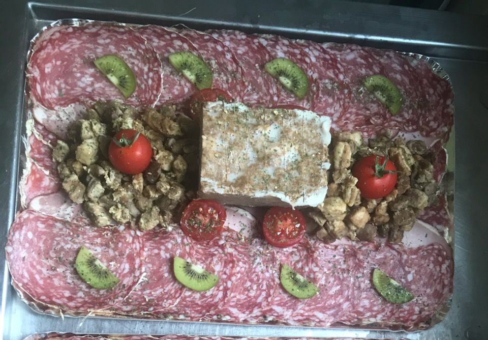 Plateau de charcuterie : salami, tranches de kiwi, tomates cerises, croûtons et un bloc de fromage.