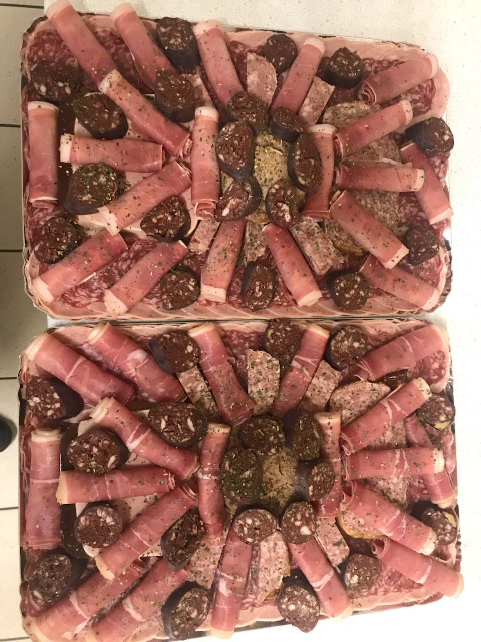 Deux plateaux rectangulaires de charcuterie, disposés selon des motifs décoratifs.