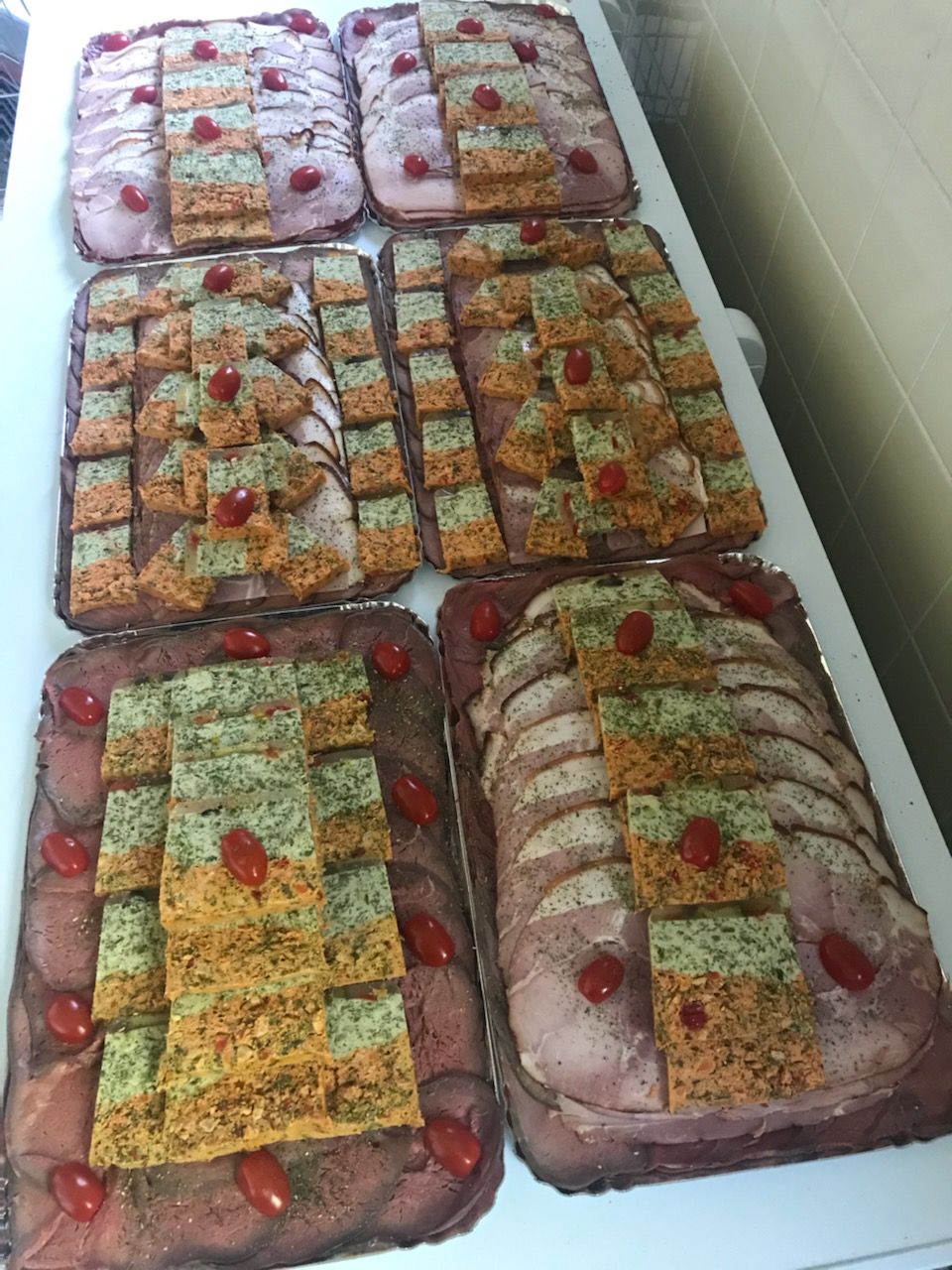 Plateaux de charcuterie, accompagnés de carrés d'amuse-gueules colorés. Garnis de tomates cerises.