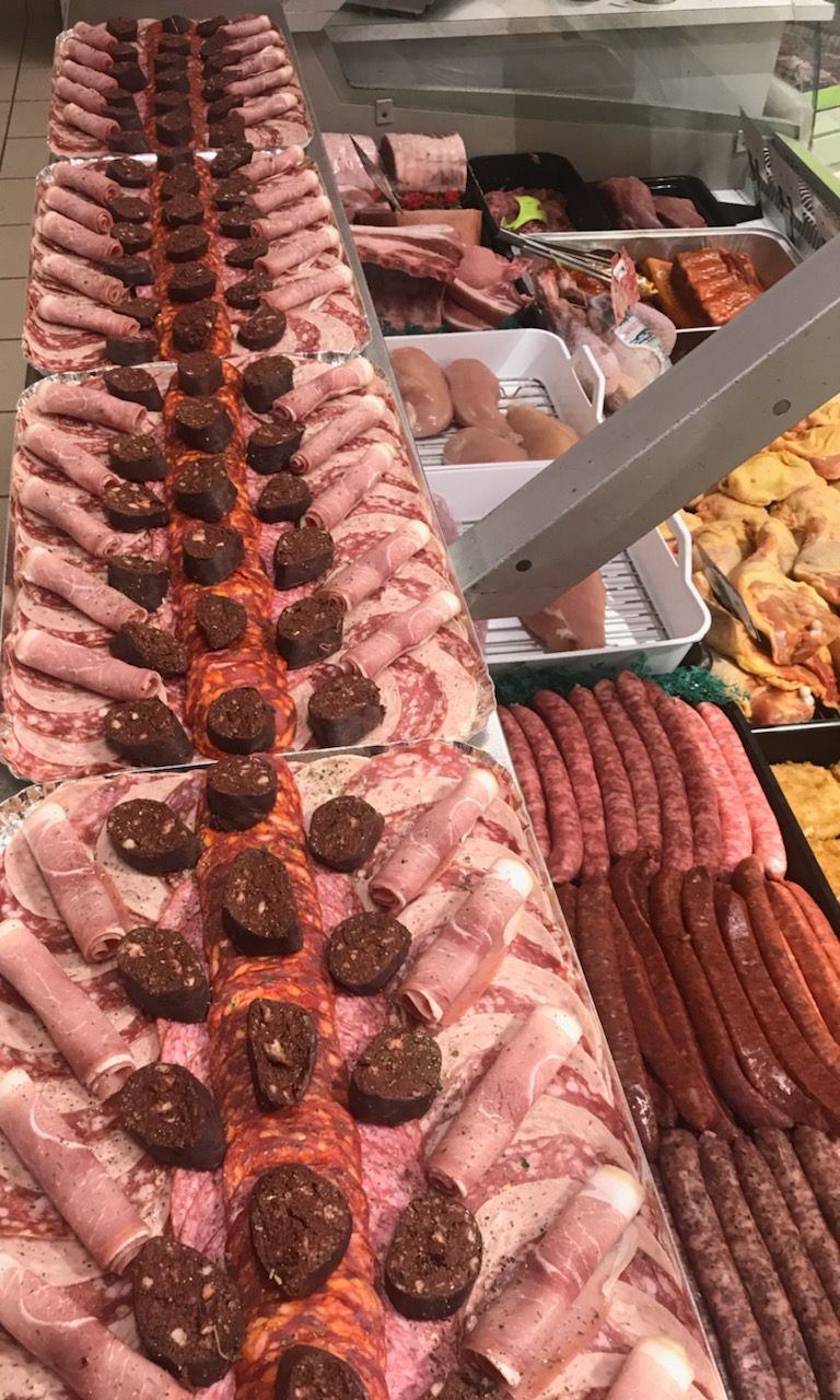 Vitrine de présentation de viande remplie de saucisses, de viandes tranchées et d'autres aliments préparés.