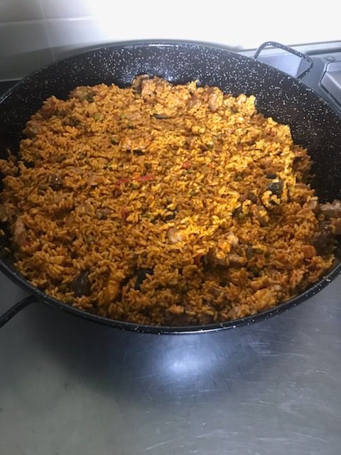 Grande poêle remplie de riz brun doré, peut-être de paella, sur une surface métallique.