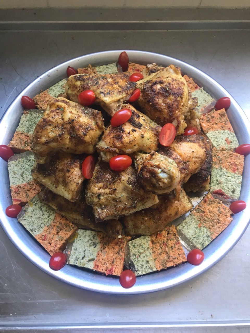 Cuisses de poulet sur plateau, entourées de craquelins colorés et de tomates cerises.
