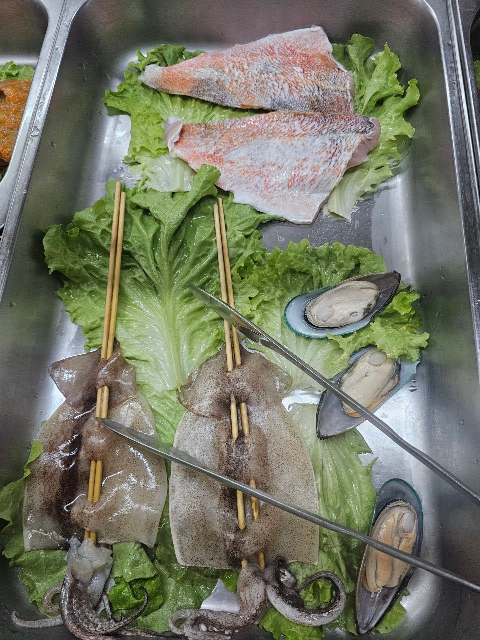 Des filets de saumon cru, deux calamars en brochette et trois moules.