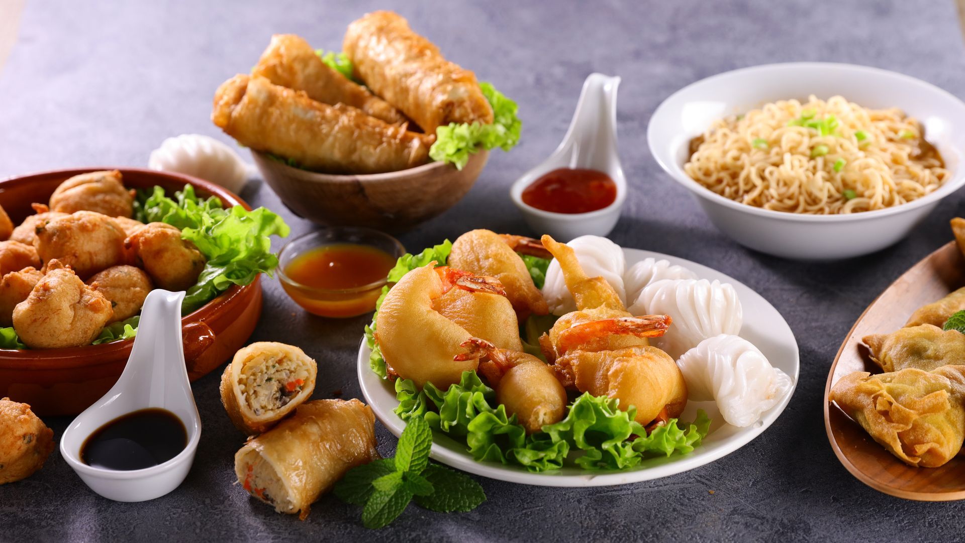 Un assortiment d'amuse-gueules asiatiques, des rouleaux de printemps, des raviolis, des crevettes et des nouilles.