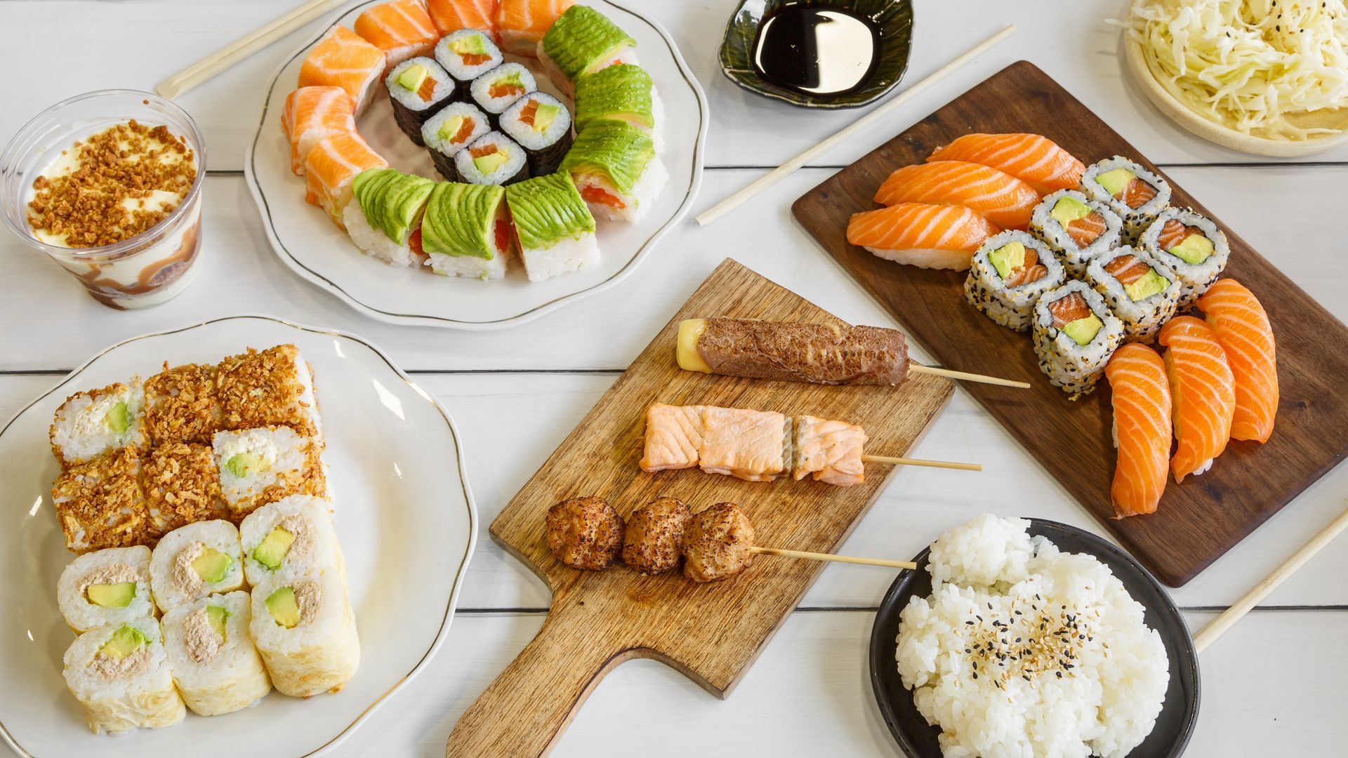 Un assortiment de sushis, sashimis et brochettes disposés sur des assiettes et une planche en bois.