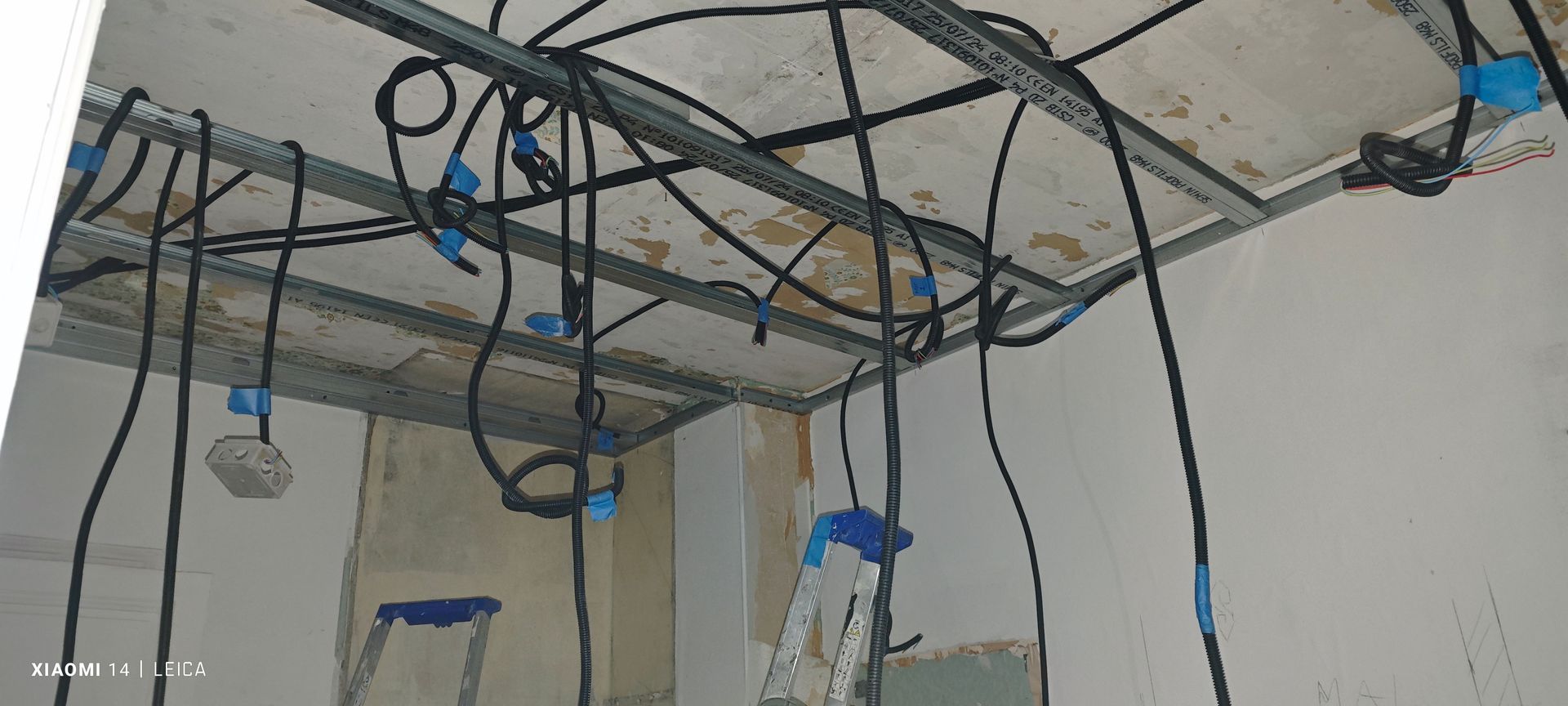 Un électricien utilise un multimètre pour inspecter une prise électrique, en portant des gants bleus.