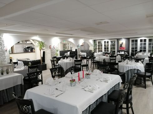 Intérieur du restaurant avec nappes blanches, chaises noires et plafonds voûtés.