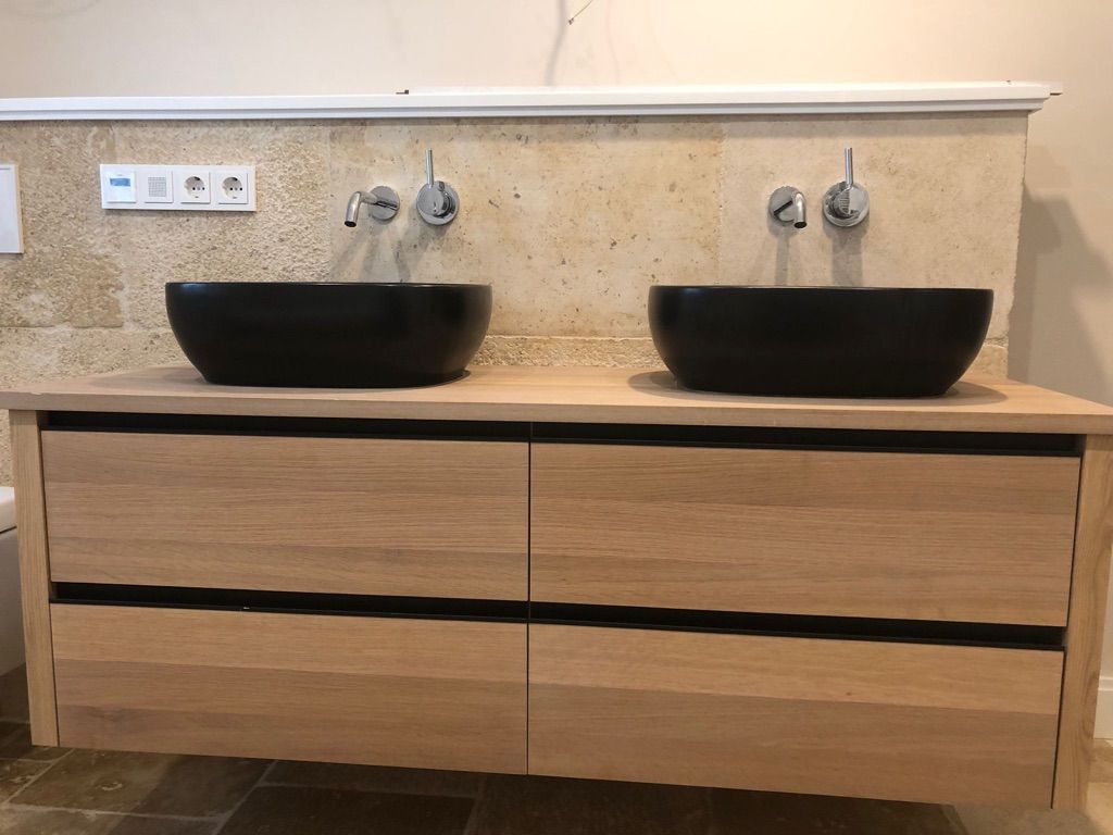 Badezimmerwaschtisch mit zwei schwarzen Waschbecken und Holzschrank.