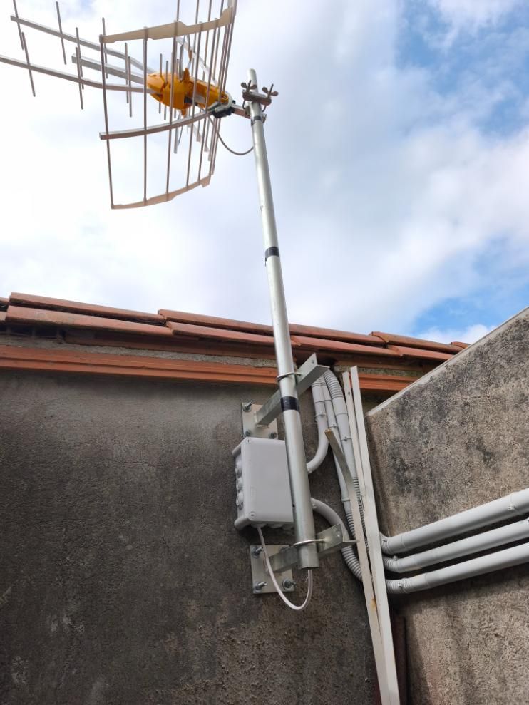 Antenas montadas en un poste en la azotea, sobre equipos eléctricos y tuberías, contra un cielo nublado.
