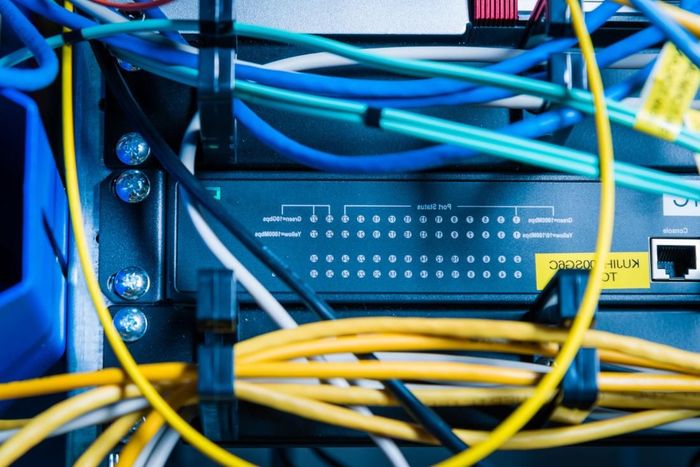 Primer plano de cables de red azules y amarillos enredados conectados a un panel de servidor.