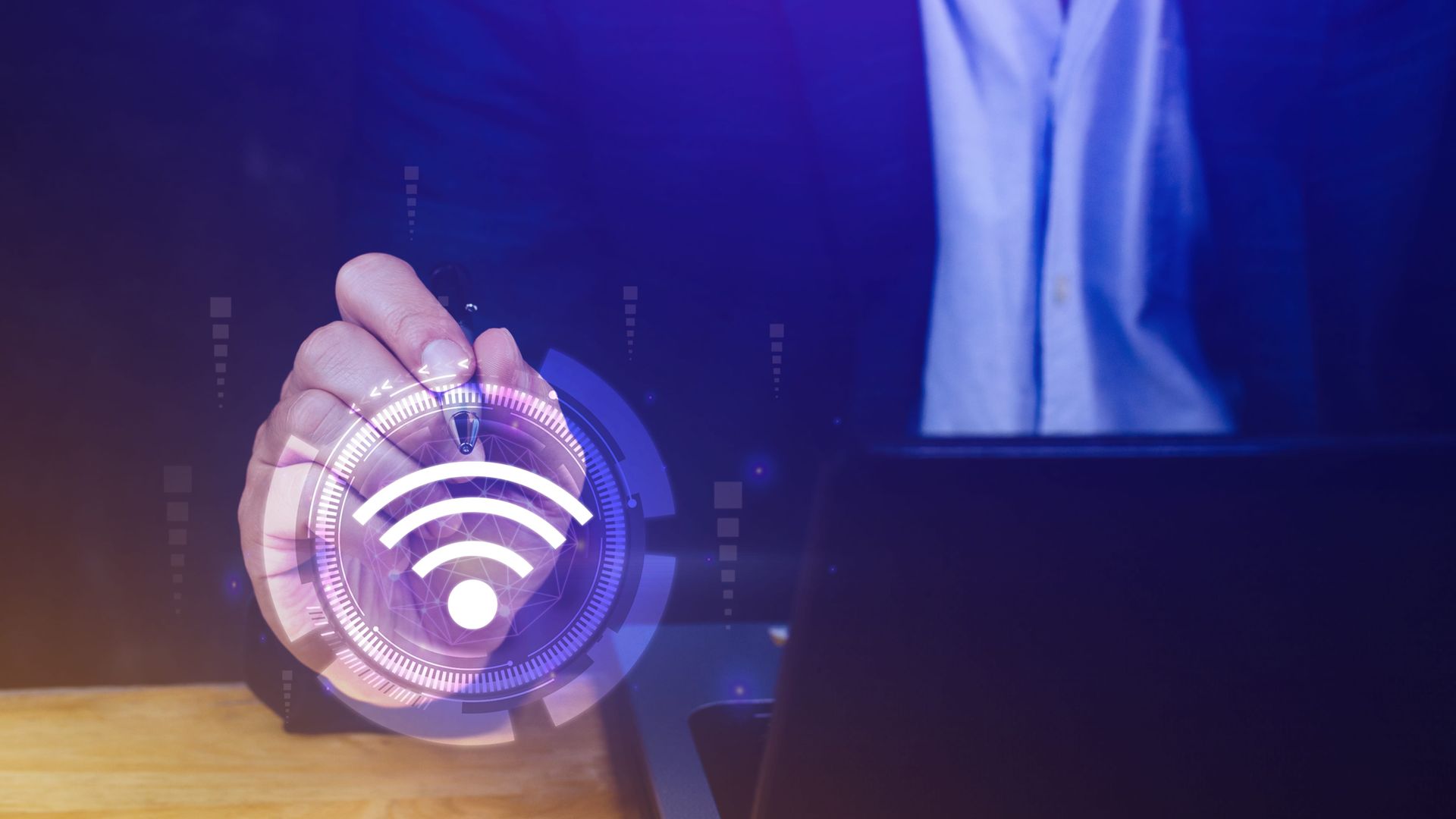 Una mano sostiene un icono inalámbrico brillante sobre una computadora portátil en un entorno tecnológico 