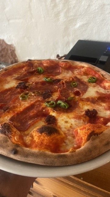 Auf einem weißen Teller steht eine Pizza auf einem Tisch.