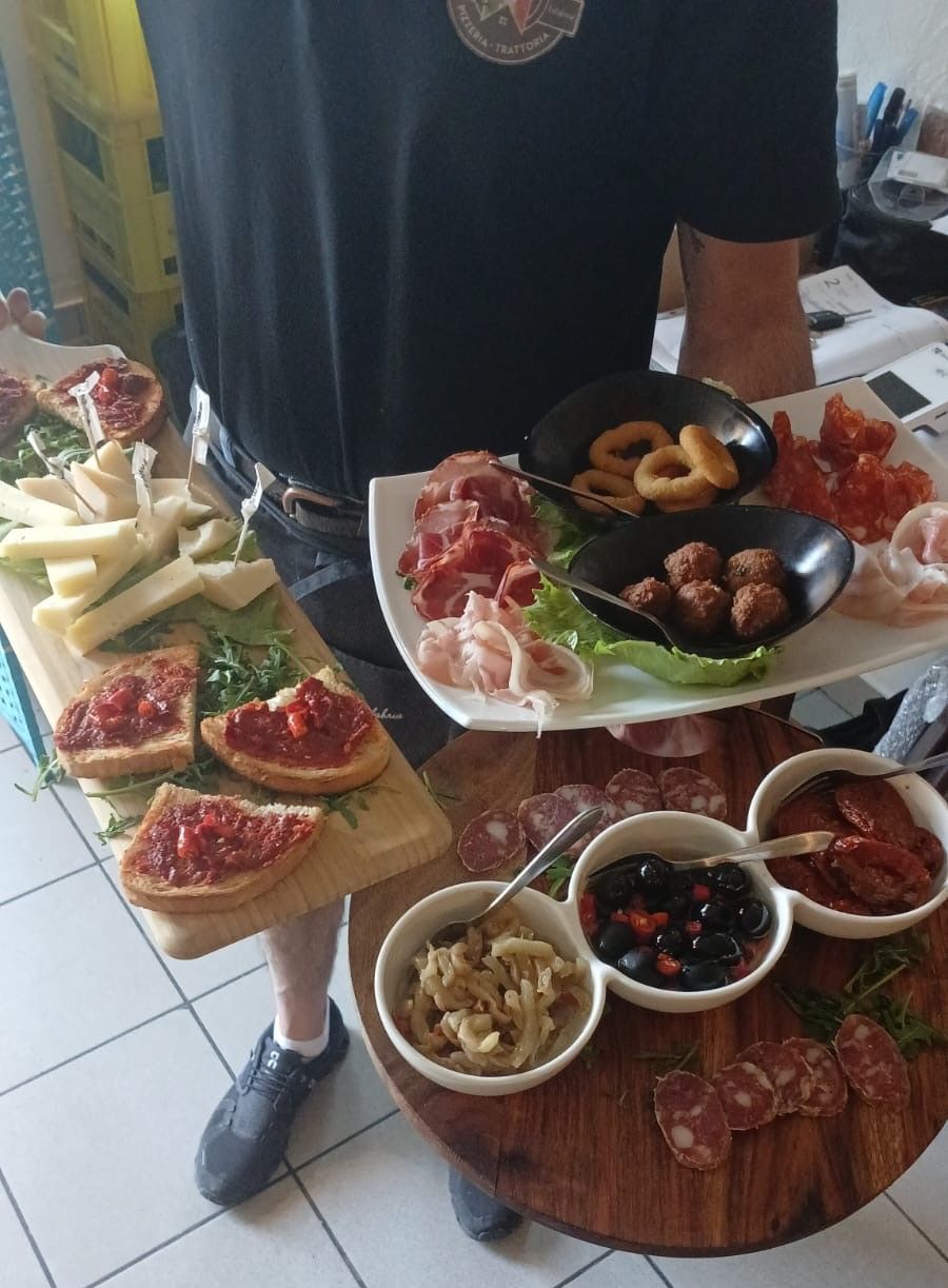 Ein Mann hält Teller mit Essen auf einem Holztisch.