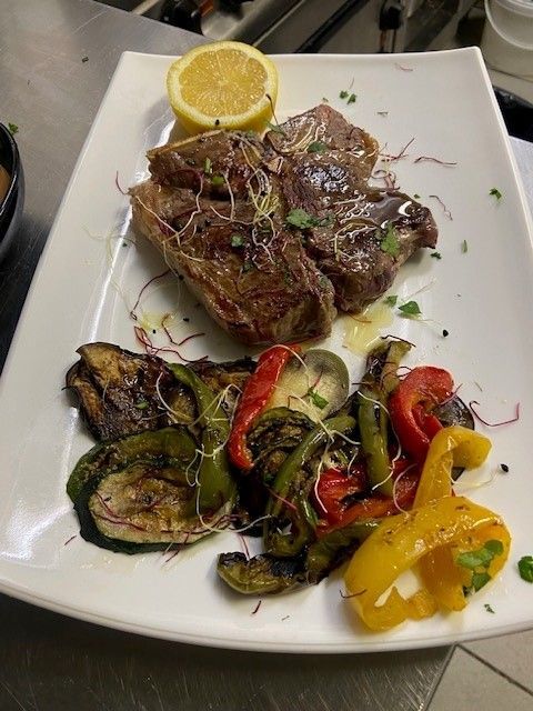 Ein weißer Teller mit Fleisch und Gemüse darauf