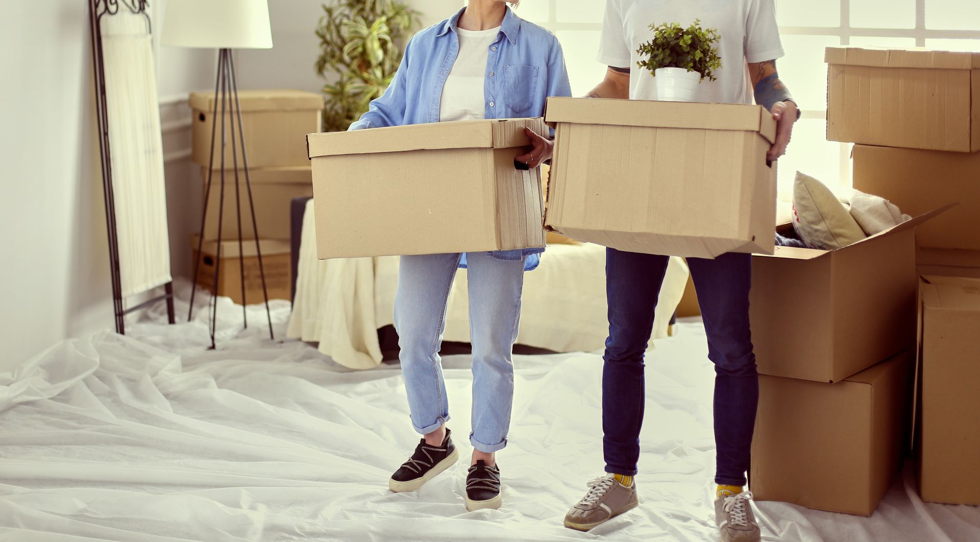 Ein Mann und eine Frau tragen Kisten in ein neues Zuhause.