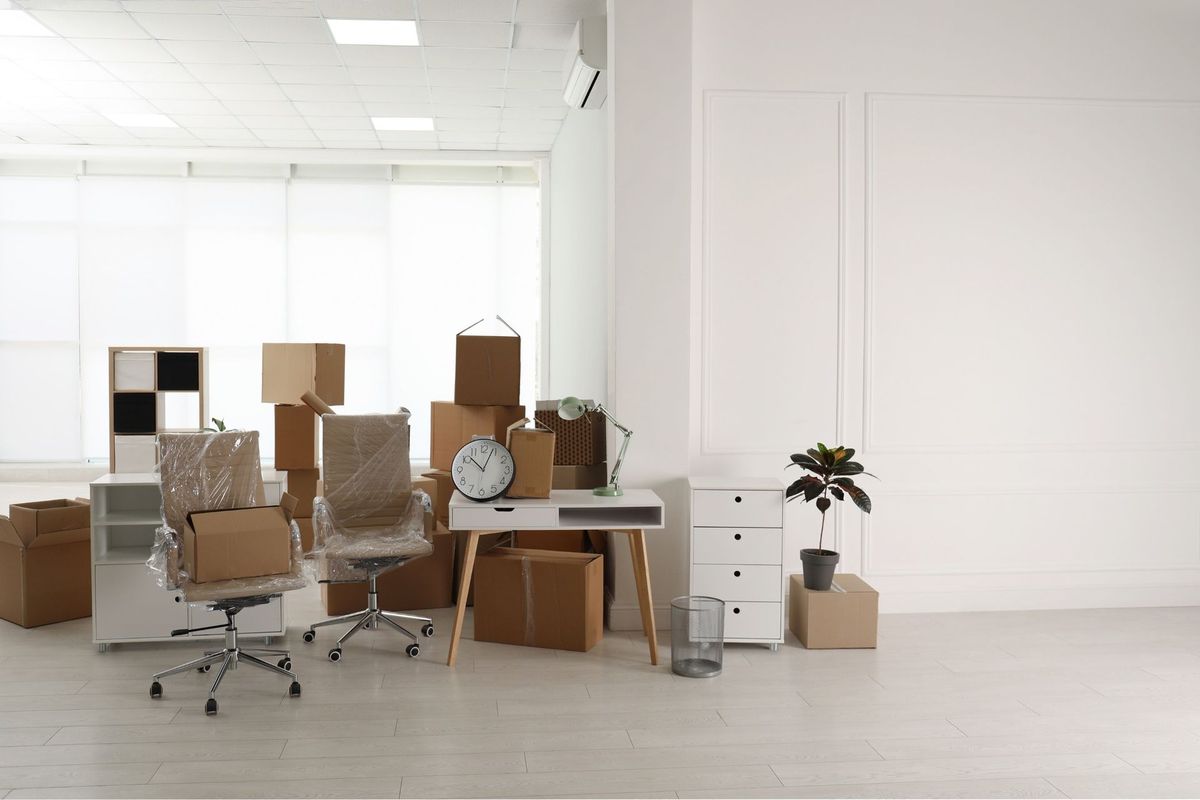 Una habitación llena de cajas, sillas, un escritorio y un reloj.