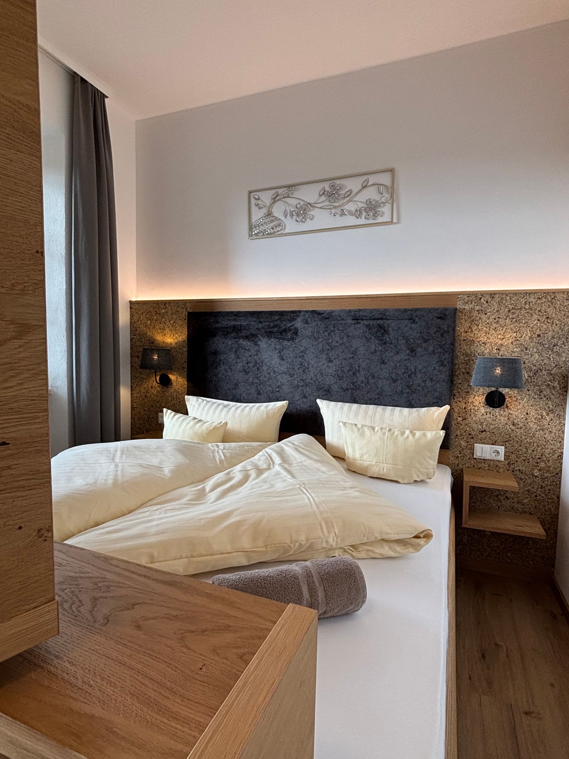 Doppelbett mit dunklem Kopfteil und einem Metallbild darüber