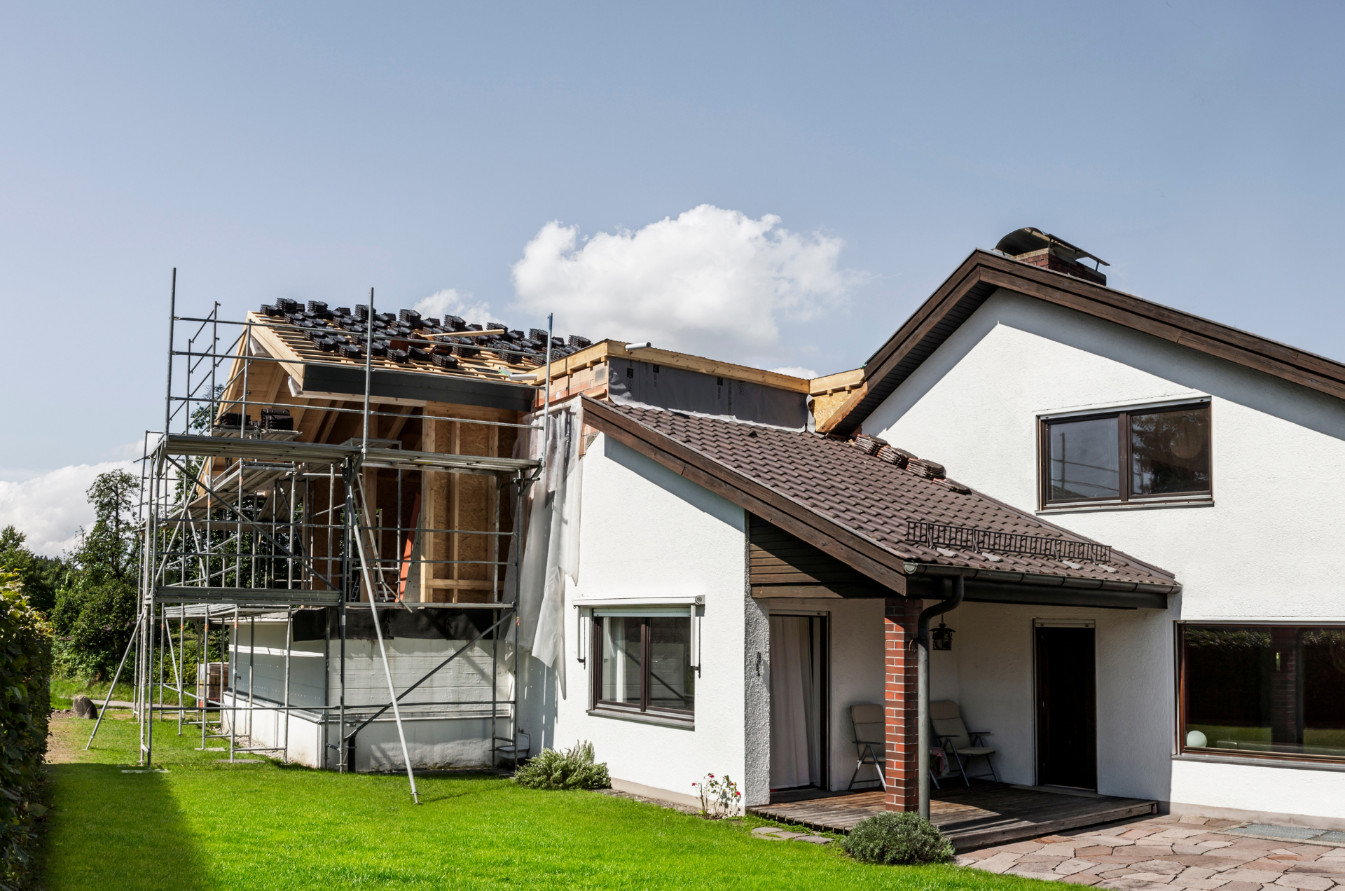 Maison en cours de réparation de toiture avec échafaudage et charpente apparente.