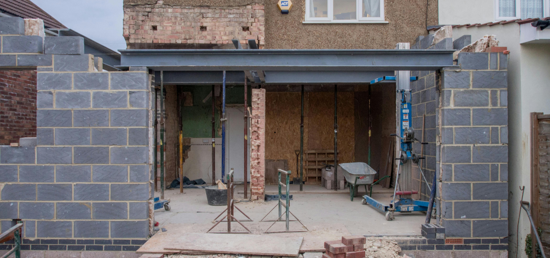 Construction d'une extension de bâtiment. Les murs en briques sont en place, supportant une poutre en acier.