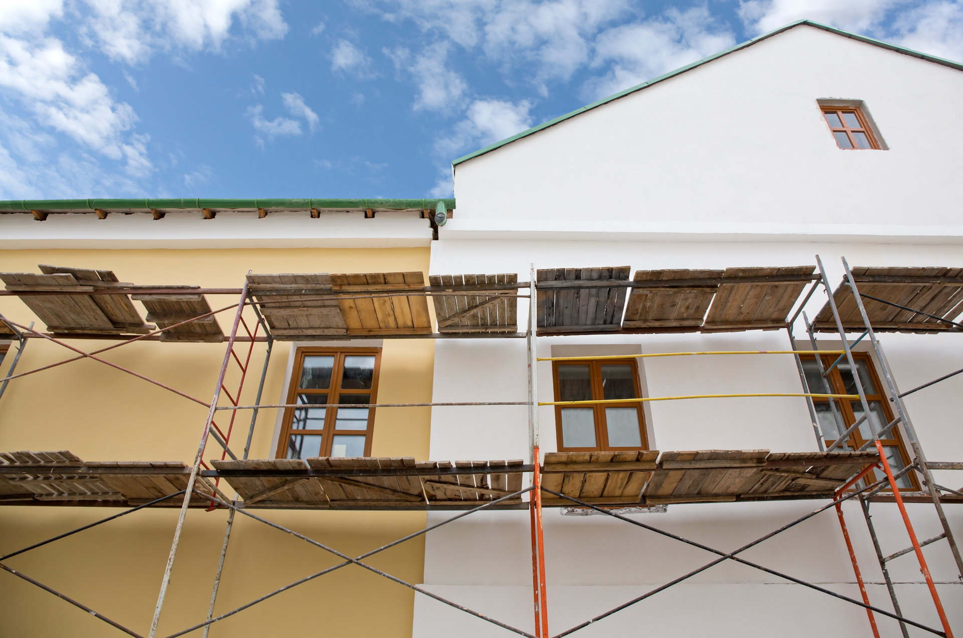 L'extérieur du bâtiment est peint avec des échafaudages ; les sections jaunes et blanches contrastent.