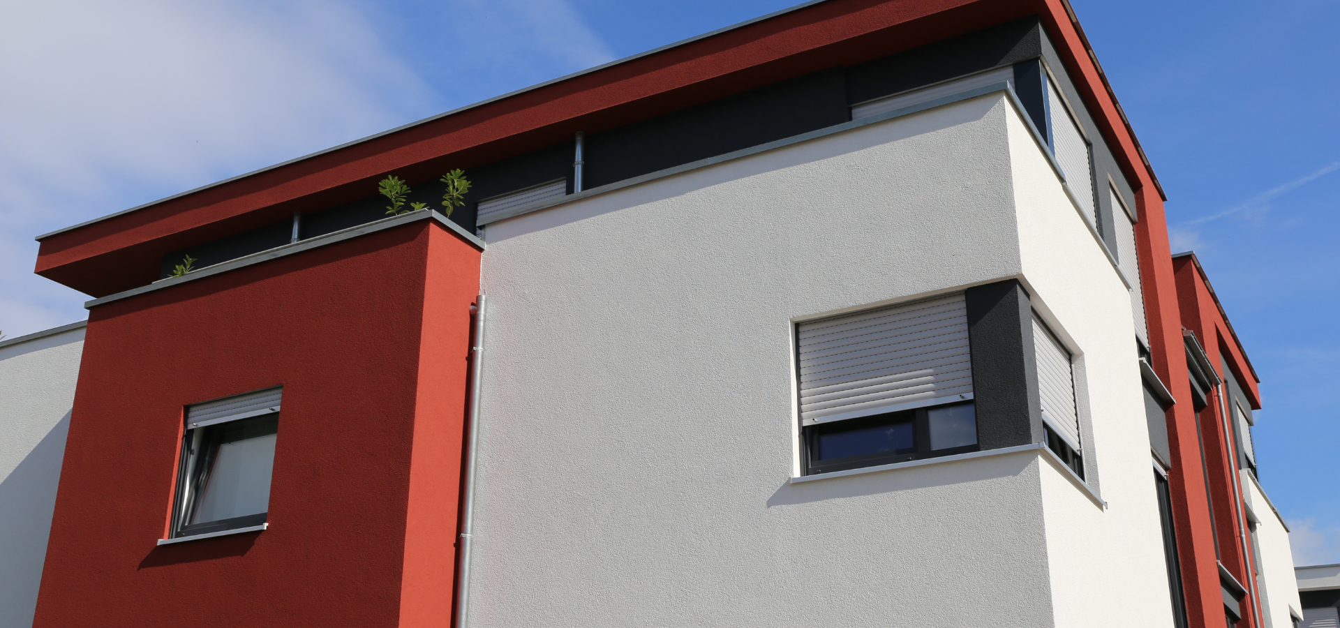 Bâtiment moderne avec façade rouge et blanche sur fond de ciel bleu.