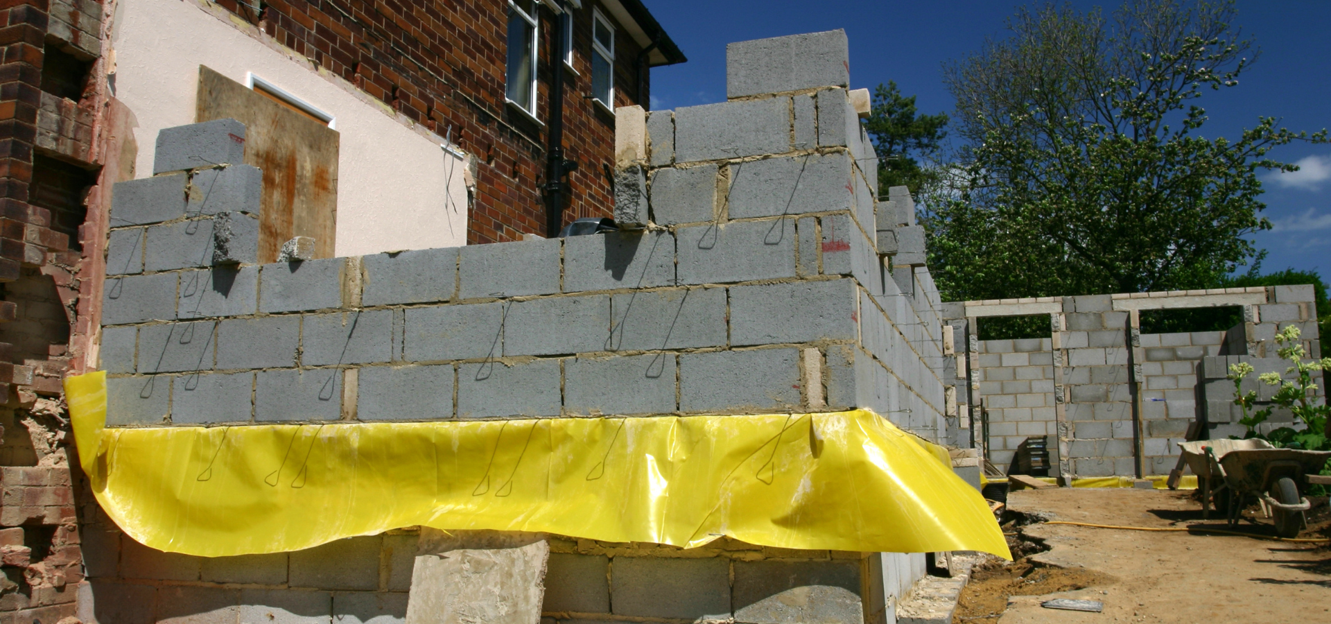 Construction d'un bâtiment en briques. L'extérieur est brut, avec des blocs de béton.