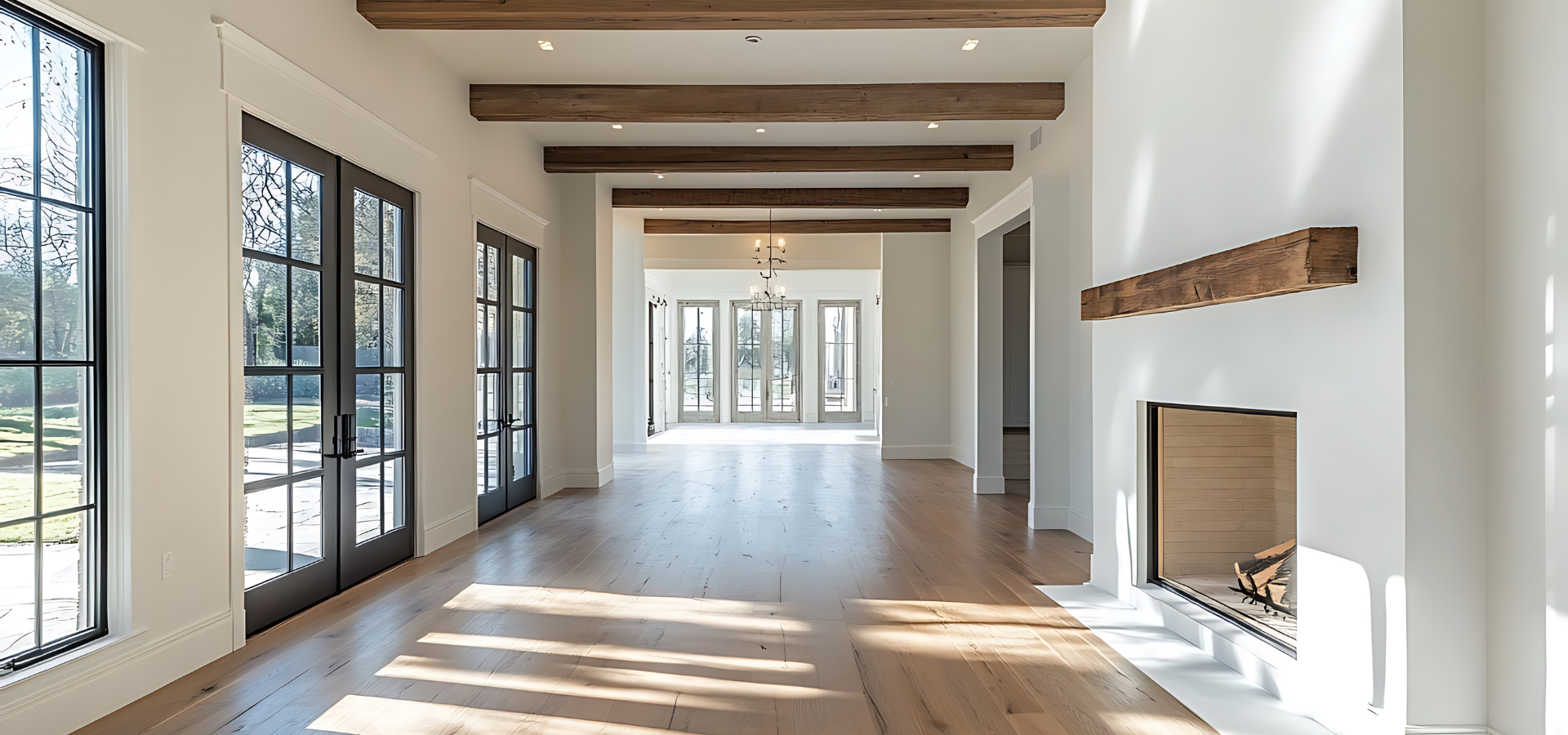 Intérieur spacieux et lumineux avec poutres apparentes, parquet et cheminée. Des portes-fenêtres s'ouvrent sur l'extérieur.