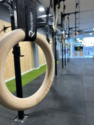 Dos personas entrenando en un gimnasio, una sosteniendo una banda de resistencia mientras