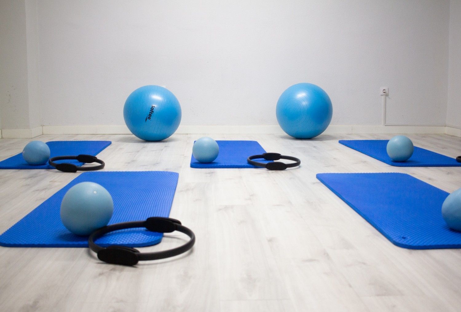 Mujer realizando la postura de yoga V-sit mientras sostiene una pelota medicinal sobre una esterilla en el interior.