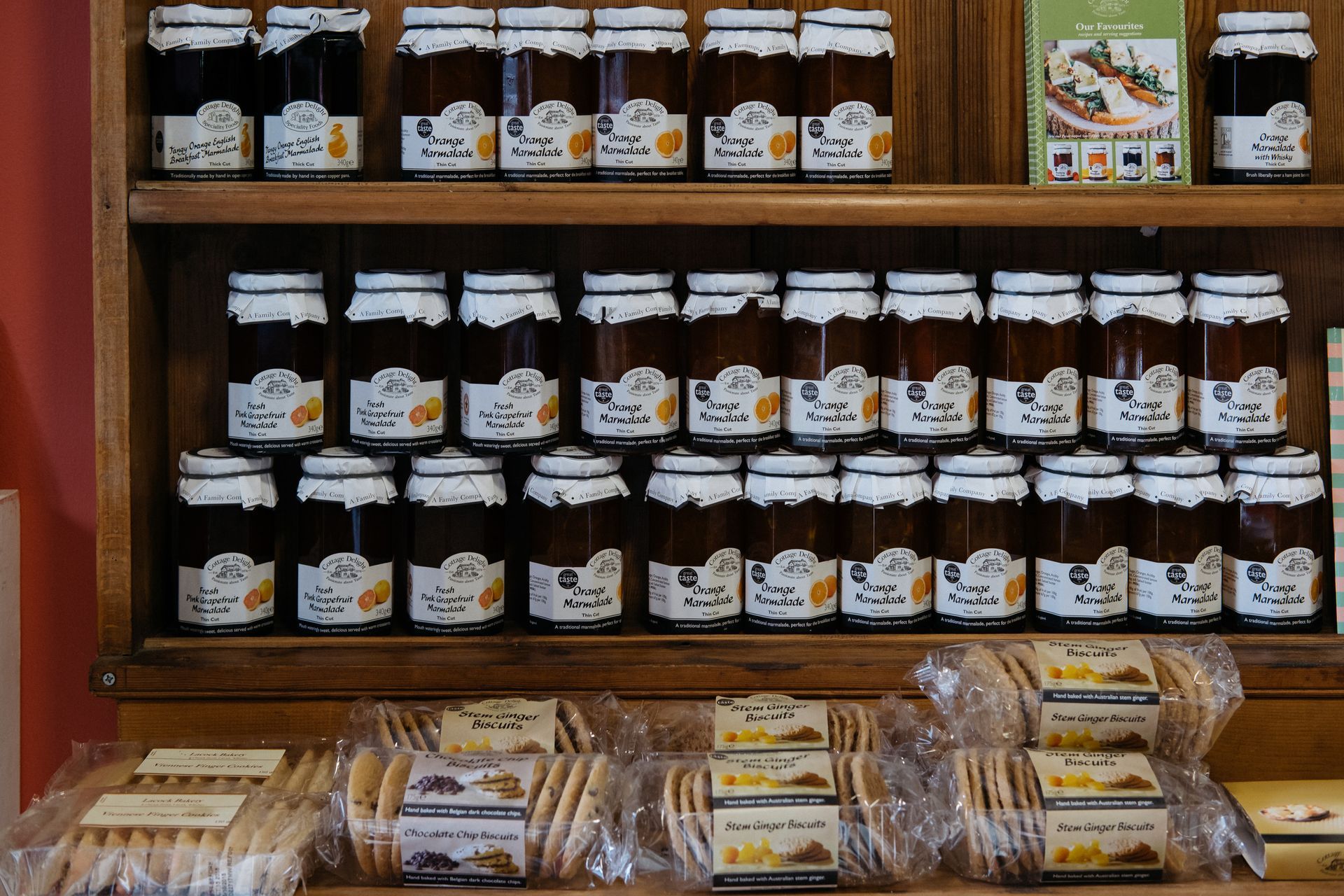 Estanterías que muestran tarros de mermelada y paquetes de galletas en una vitrina de madera.