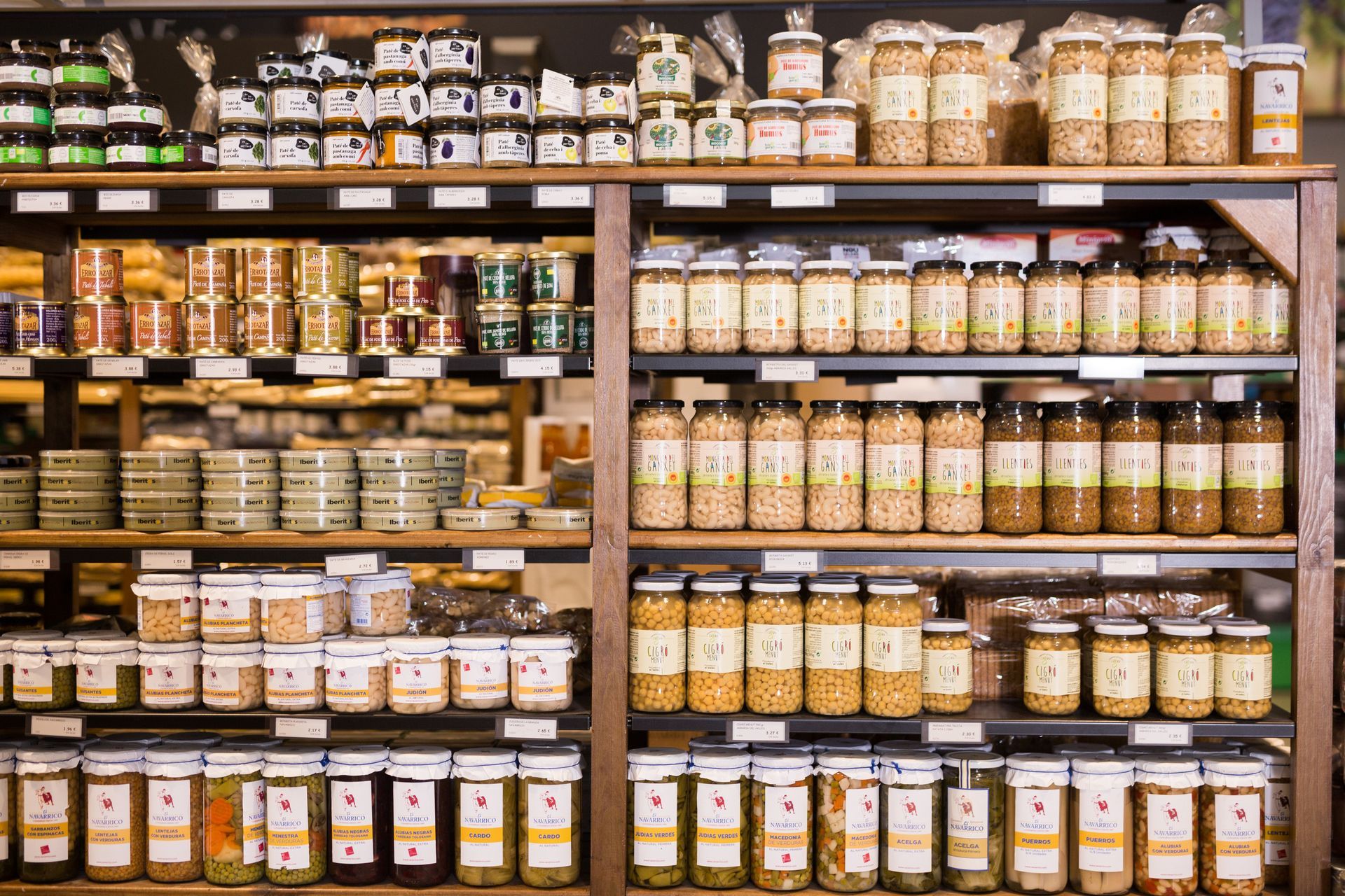 Estanterías repletas de diversos frascos de productos alimenticios, organizados en una tienda.