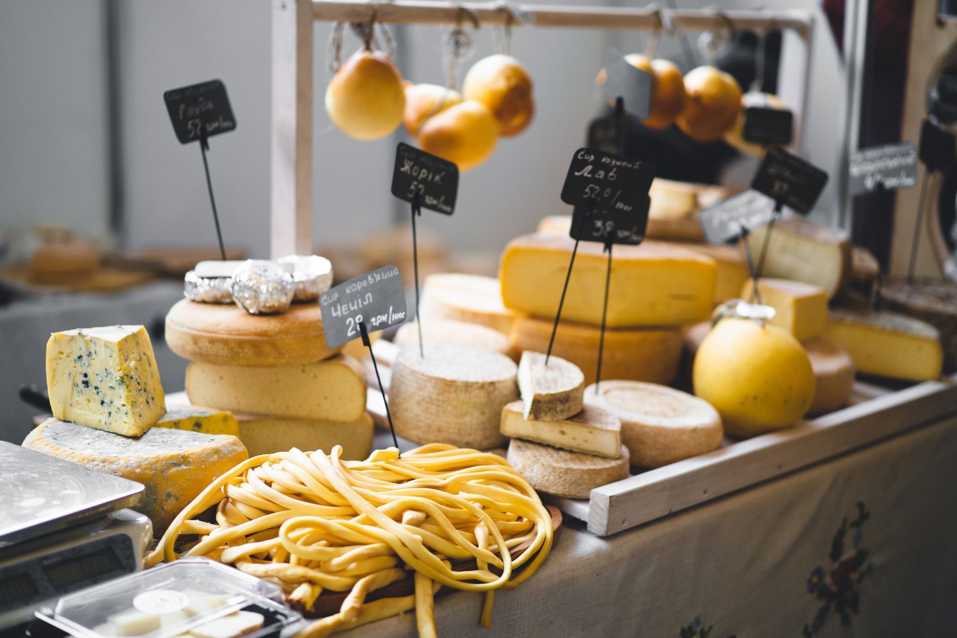 Exhibición de quesos en un mercado, con diversas ruedas y bloques, junto con pasta.