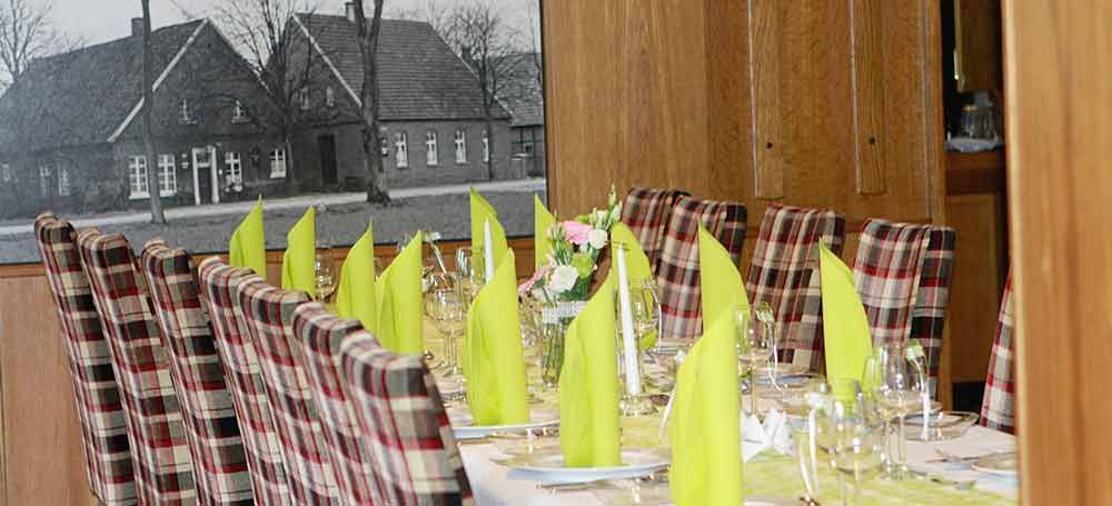 Ein langer Tisch mit Tellern, Gläsern, Servietten und einem Bild an der Wand.