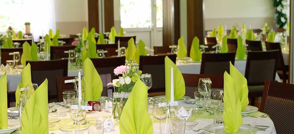 Ein Restaurant mit Tischen und Stühlen mit grünen Servietten und Kerzen