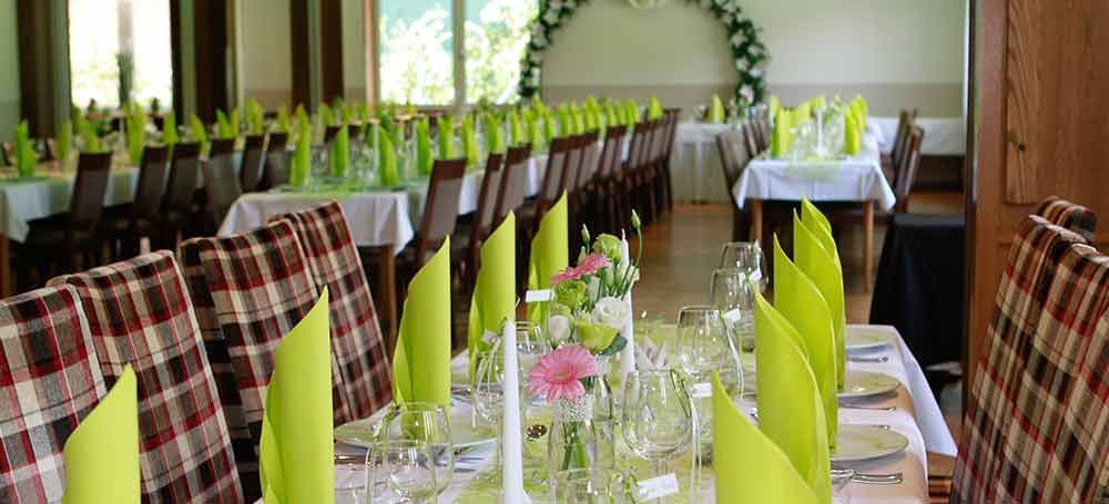 Ein großer Raum mit Tischen und Stühlen, aufgestellt für einen Hochzeitsempfang.