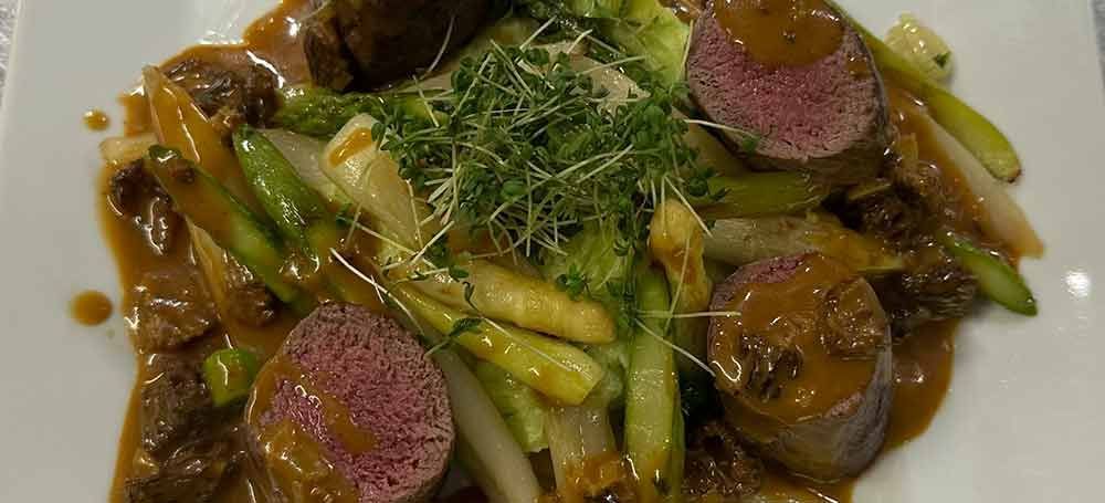 Ein weißer Teller mit Spinat, Schinken und Kartoffeln