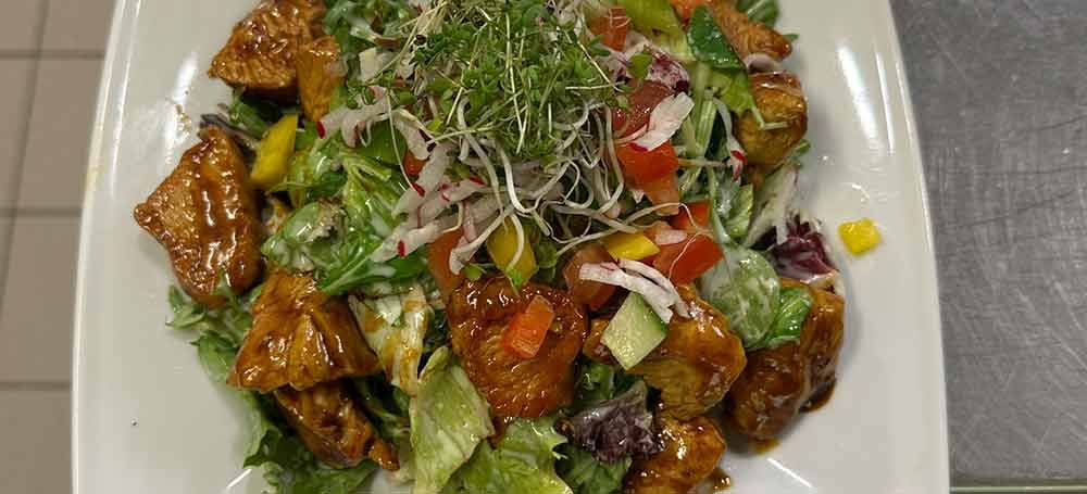 Ein Salat mit Tomaten, Gurken, Fetakäse und Salat auf einem Teller.