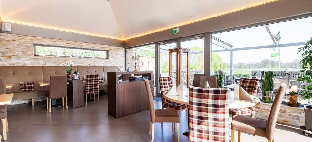 Ein Restaurant mit Tischen und Stühlen und vielen Fenstern.