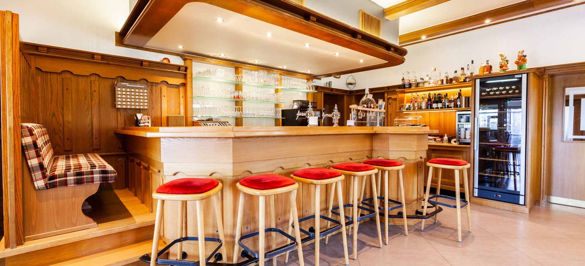 Eine lange Holzbar mit roten Hockern in einem Restaurant.