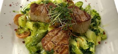 Ein weißer Teller mit weißem Spargel, Schinken und Zitrone.