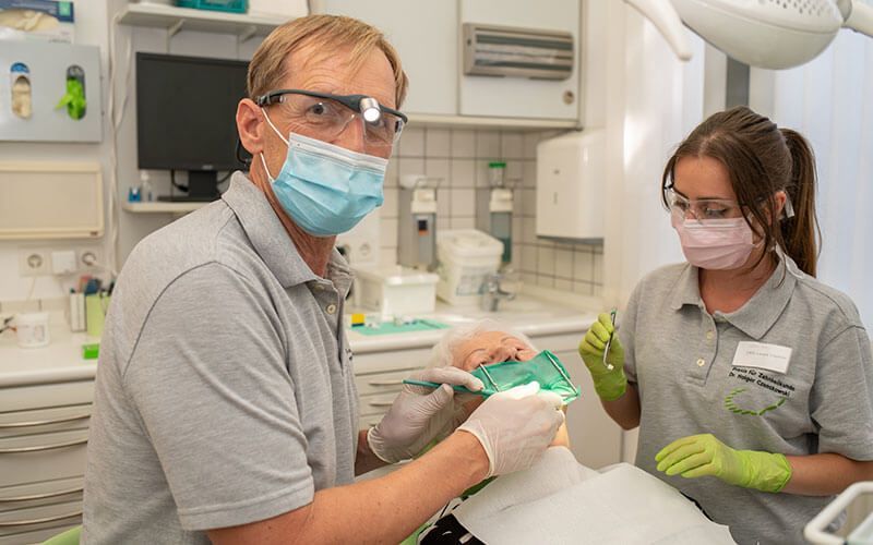 Ein Mann und eine Frau behandeln in einer Zahnarztpraxis einen Patienten.