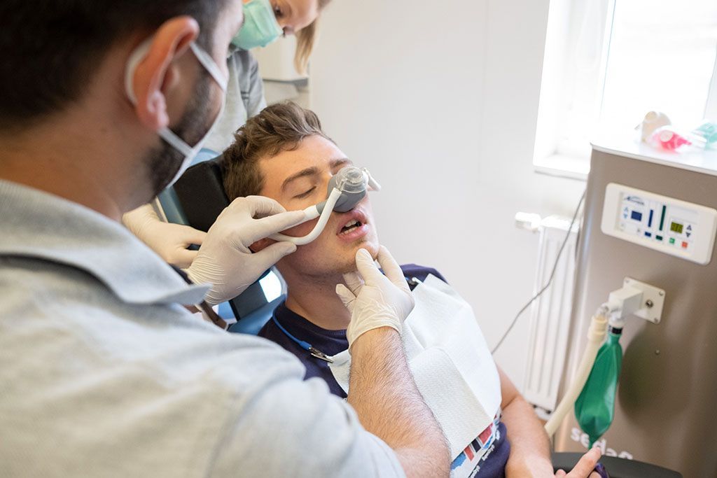 Ein Mann sitzt mit einer Sauerstoffmaske im Gesicht in einem Zahnarztstuhl.